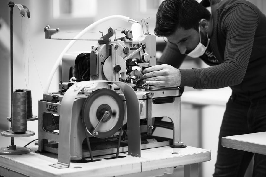 Ibrahim, couturier à l'atelier Dao, sur une machine à faire des boutonnières de marque Reece