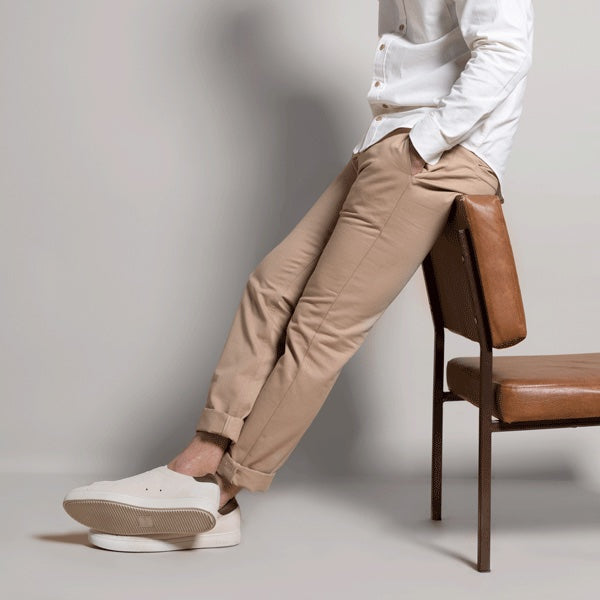 Pantalon chino eco responsable beige porté par un mannequin adossé sur une chaise 