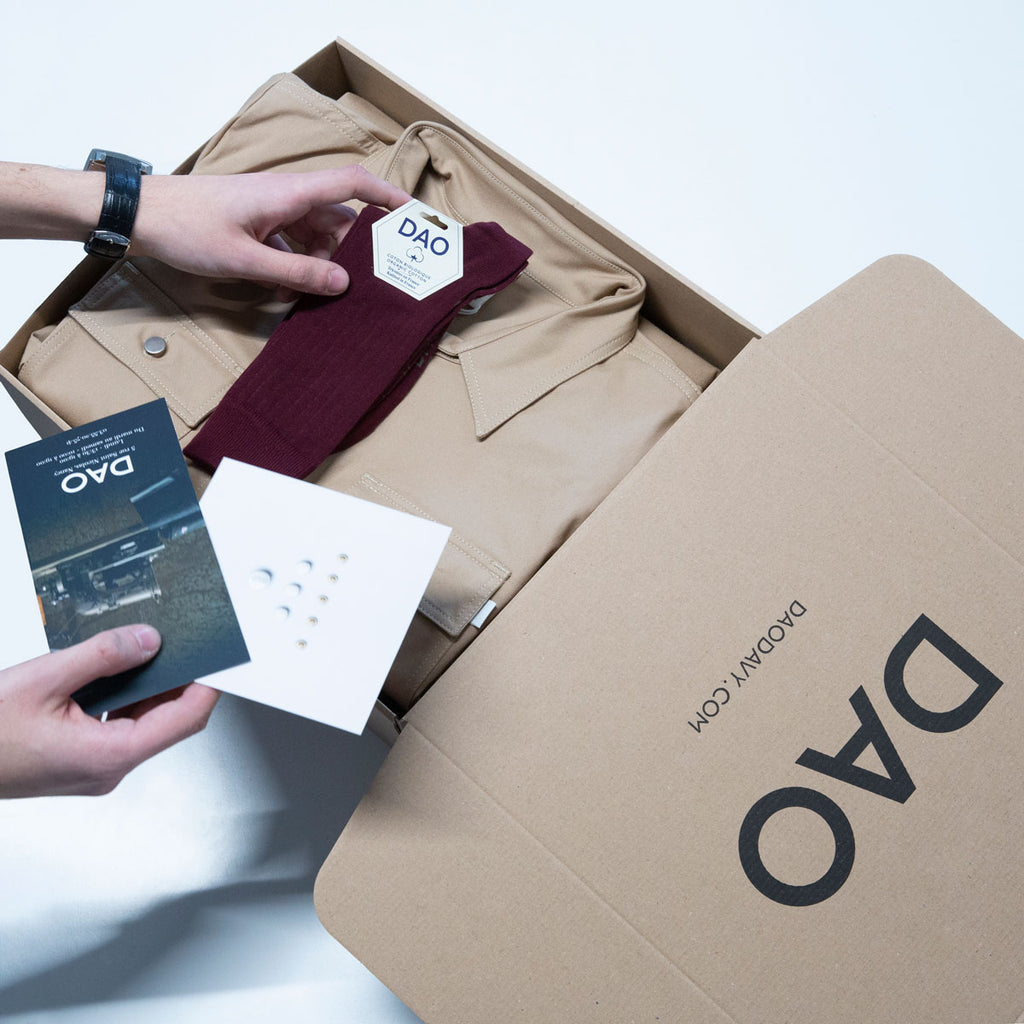 Boite d'expédition Dao avec des chaussettes bordeaux tricotées en France et une robe saharienne beige en coton biologique Made in France