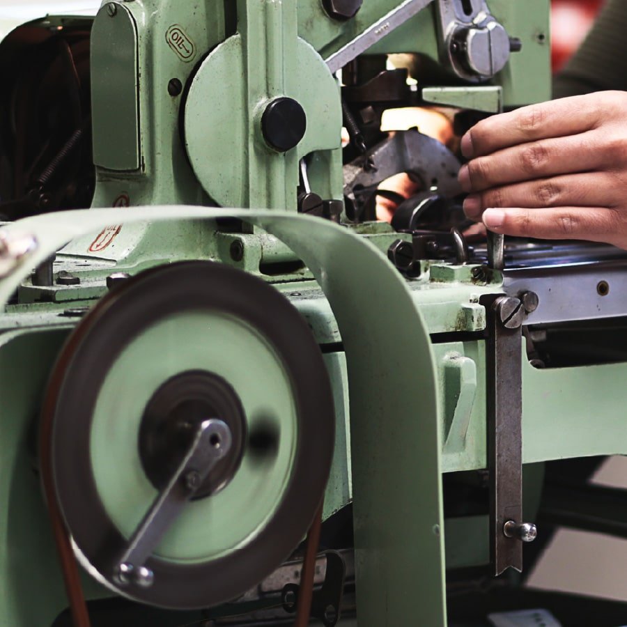 gros plan machine à coudre boutonnière et main sur la machine à l'atelier DAO Jeans Made in France